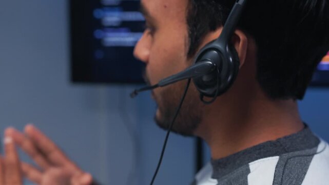 Professional Indian Male IT Support Agent working on desktop computer, providing Assistance to a Customer while Online Live support and Problem Solving on Headset Communication in Call Center Office.