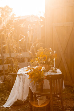 Cozy autumn table decoration for a thanksgiving party outdoors. Centrepiece with sunflowers, candles, pumpkins as decor. Elegant wedding fall arrangement, beautiful setting for a romantic lunch.