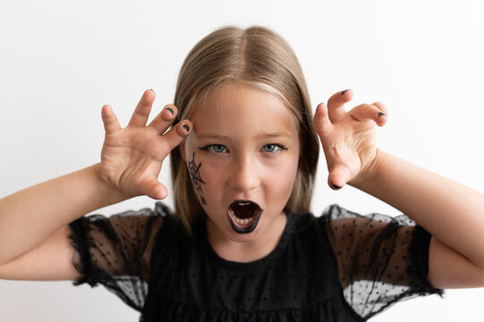 Close up portrait of little girl growling with claw hands for Halloween
