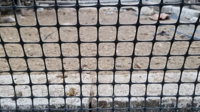 Close up of black plastic mesh fence grid pattern over concrete bricks in construction site