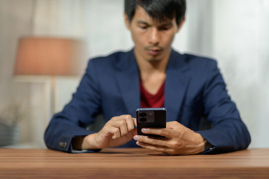 Young man using smartphone at home, focused and engaged, casual business attire, indoor setting, modern technology