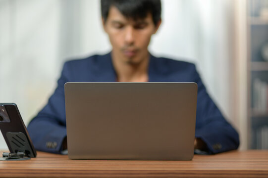 Young Man Using Laptop at Desk in Modern Office Environment