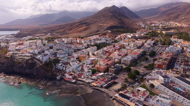Ambient drone exploration of the Morro Jable town known for its beaches, like vast Playa del Matorral, with its Morro Jable Lighthouse. Drone POV of Fuertaventura Island.A town surrounded by mountains