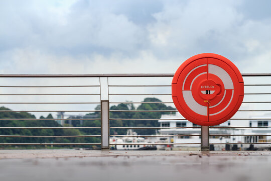 lifebuoy by river for rescue in emergency on cloudy day, floating rescue tool thrown to a person in the water to stop them from sinking, shallow depth of field, copy space
