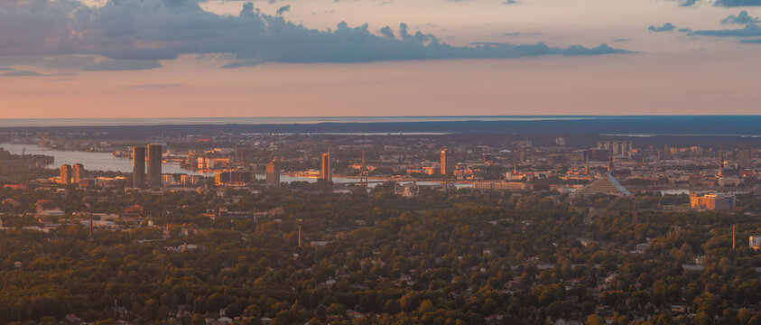 Panoramic aerial view of the town of Marupe stretching towards the distant skyline of Riga and the Gulf of Riga beyond, at sunset. Marupe, Latvia.