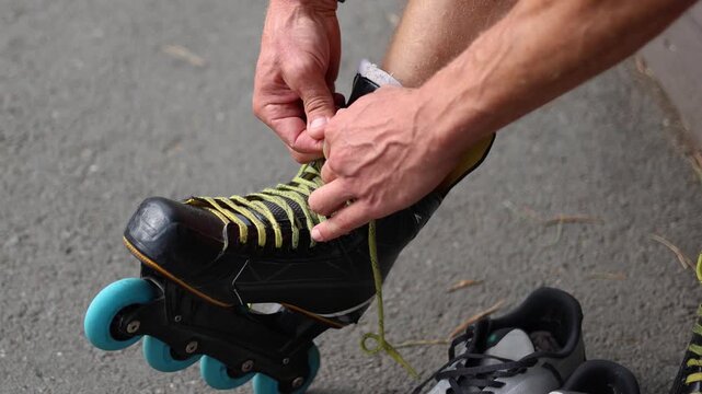 Slow motion 4k footage of a middle-aged man's foot - he ties the laces of his roller skates. Preparing practice his hockey technique on the asphalt.