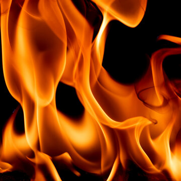Abstract close-up of vibrant orange and yellow flames burning dynamically against a black background. Halloween background