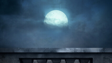 Fototapeta premium A view from a stone balcony looking out at a bright full moon shining through dramatic, moody night clouds in a dark blue sky. Halloween background