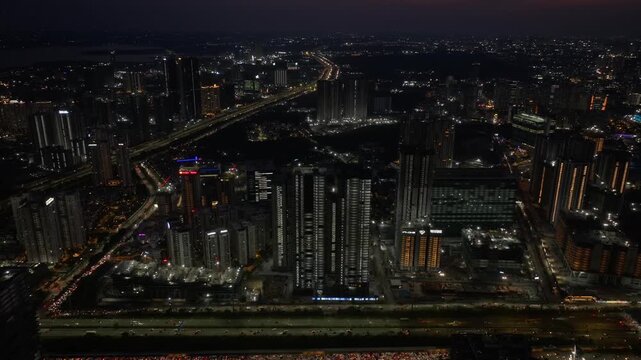 High angle view of illuminated buildings with outer ring road, traffic flow and IT park at Financial District, Nanakramguda, hyderabad, telangana, india. night time, push back shot, drone shot, 4k.
