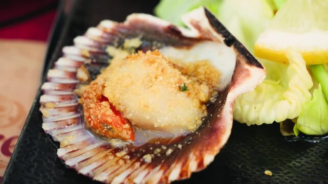 Baked scallop served in its shell with fresh salad and lemon. High quality 4k footage