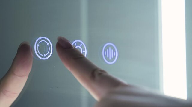 Close-up of a finger pressing illuminated touch controls on a smart bathroom mirror. Modern home automation interface with LED icons for lighting and built-in features. High quality 4k footage