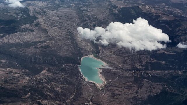 4k aerial video footage - flying along Joes Valley Reservoir with Joes Valley Dam, surrounded by Manti&ndash;La Sal National Forest - partly covered with a white cumulus cloud - located in Emery County, USA
