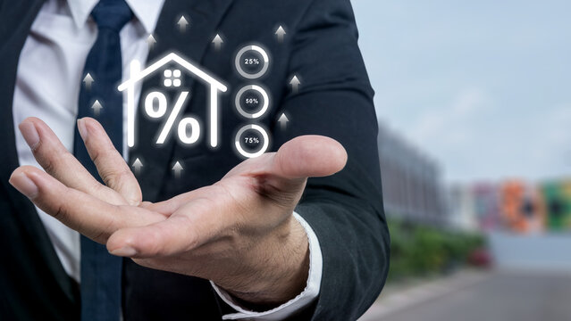 Businessman holding a virtual house icon with a percentage sign, representing mortgage interest rates and real estate investment. Concept of business growth or finance