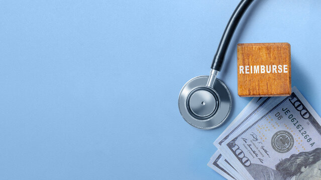 Stethoscope, dollar bills, and wooden block with word 'REIMBURSE' on blue background, representing healthcare costs. Concept of Reimburse