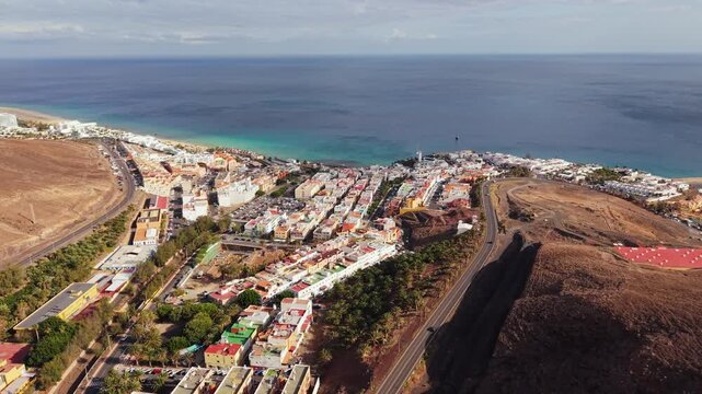 Ambient drone exploration of the Morro Jable town known for its beaches, like vast Playa del Matorral, with its Morro Jable Lighthouse. Drone POV of Fuertaventura Island.
