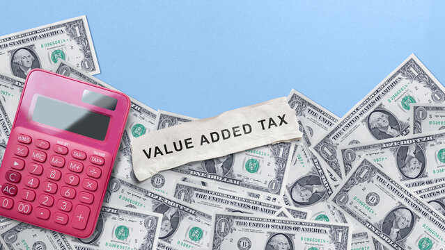 Value Added Tax text on paper with US dollar bills and a pink calculator on a blue background. Financial regulation and tax compliance concept