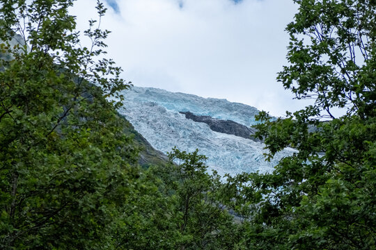 Jostedalsbreen Glacier Face Viewed Through Green Forest Trees, Norway