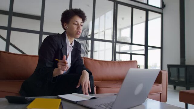 Businesswoman Speaking and Taking Notes During Remote Meeting