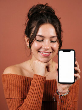 Woman smiling while holding smartphone outdoors