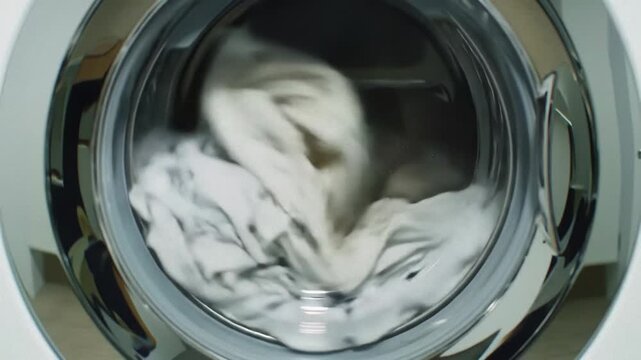 White clothes spin in chrome washing machine drum