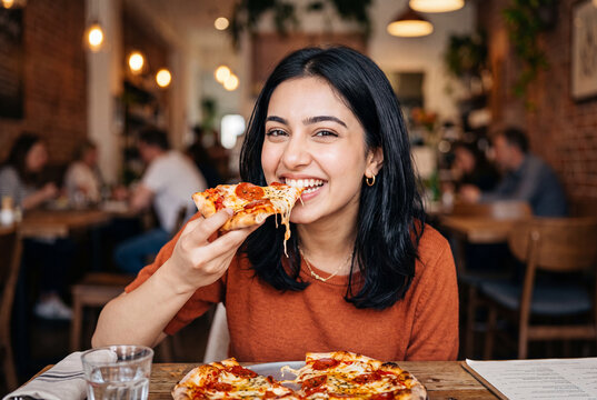 Woman happily eating pizza in cozy restaurant