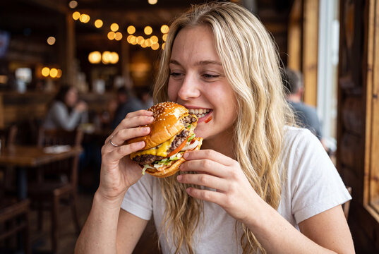 Woman eating burger in cozy restaurant