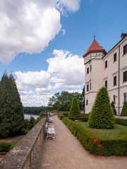 Garden terrace of Konopiště Castle near Benešov, Czech Republic, overlooking landscaped park and lake beneath a blue sky with dramatic clouds. Historic castle gardens in summer. © Marek