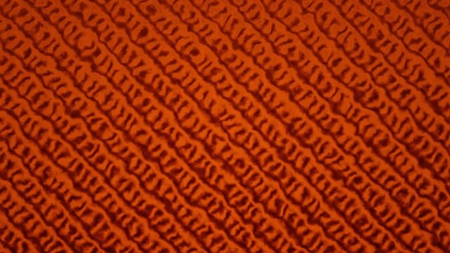 A seamless and warm orange fabric background features a consistent knitted texture.
