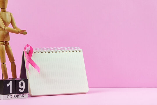 Breast cancer awareness calendar date October 19 with pink ribbon and notepad on background