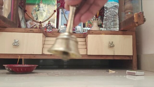 Hand ringing brass bell during Hindu prayer ritual in home temple