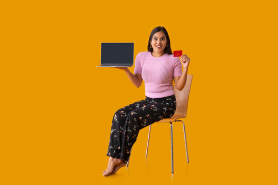 Indian girl cheerfully posing  with laptop and debit card