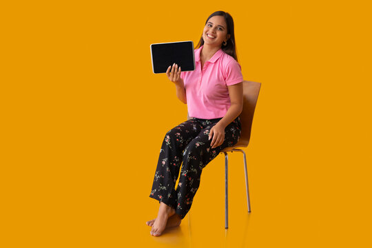 Happy Indian girl showing her tablet while sitting on chair