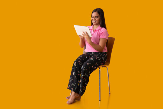 An Indian girl watching tablet while sitting on chair