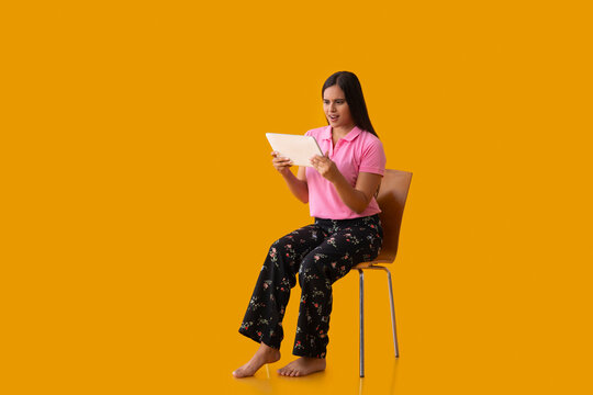 An Indian girl watching tablet while sitting on chair