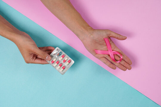 Breast cancer treatment concept with pink ribbon and pill blister pack held in hands