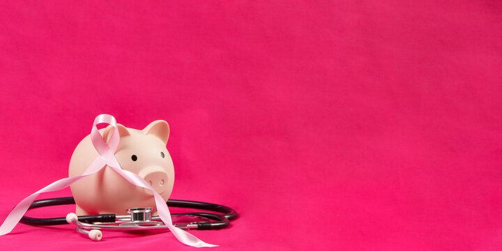 Breast cancer research fundraising concept with pink ribbon piggy bank and stethoscope on pink background