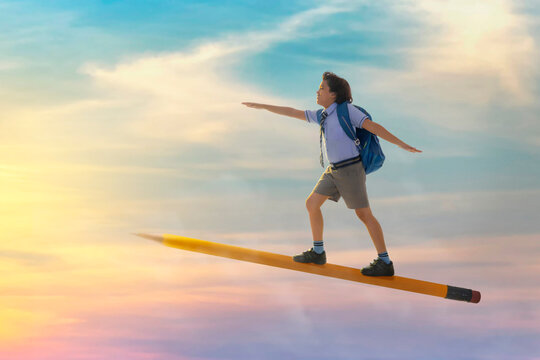 portrait of a boy in school uniform flying on pencil in the sky