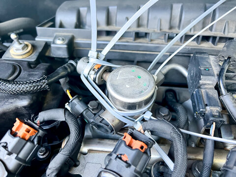 Temporary fix made to a car engine using cable ties to hold the fuel hose in place made by a breakdown company mechanic.