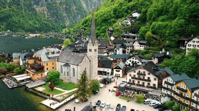 Cinematic aerial drone footage of Hallstatt surrounded by lush green forests, crystal-clear lake, and majestic Alpine mountains.