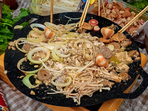 Street Food Stir Fry with Mushrooms, Chicken, Sausages, and Onions on Hot Griddle