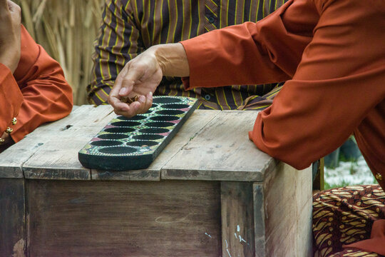 Dakon, also known as Congklak, is a traditional Indonesian board game played by two people using a wooden board with holes and seeds, shells, or pebbles.