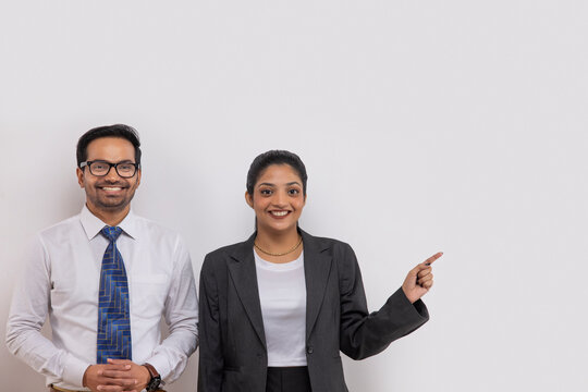 Portrait of a beautiful corporate couple looking at camera with smile and pointing elsewhere