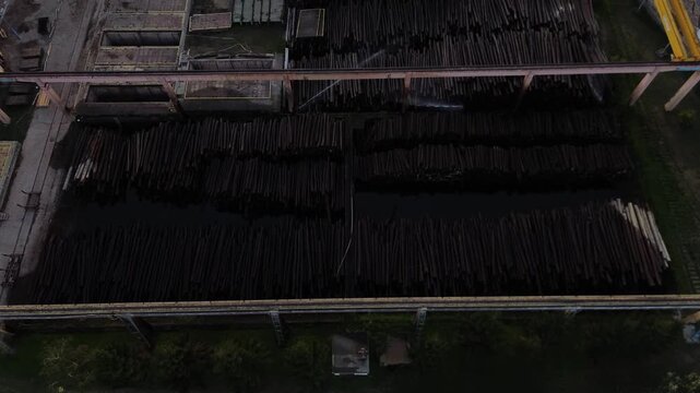 industrial wood processing site. stacks of timber are neatly organized, likely awaiting transport or further processing at sawmill. wood wetting system, water spray system for lumber, og sprinkling