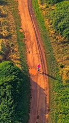 Obraz premium A senior adult jogs along a dirt path surrounded by lush greenery, highlighting their dedication to a healthy lifestyle in a serene natural setting.