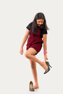 Portrait of little girl trying on high heel shoes