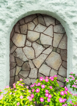 Catharanthus Roseus or Vinca flower with stone wall with arched nichein garden