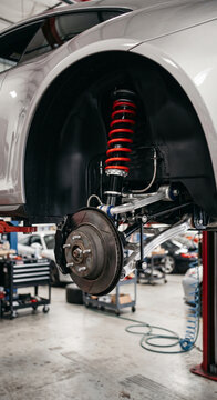 Red adjustable coilover suspension installed in a wheel well with the wheel removed. Clear lighting emphasizes its fitment, surfaces, and functional performance design.