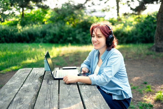 Stress-free work environment. Young woman enjoying remote work in sunny nature park.