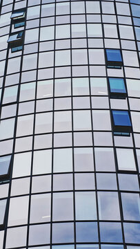 Contemporary glass facade of a commercial skyscraper, reflecting the urban environment and sky, symbolizing business and progress