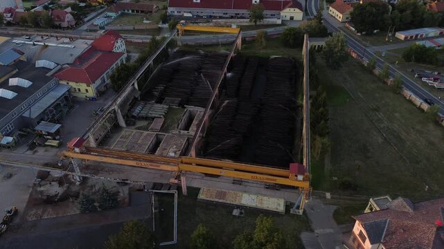 industrial wood processing site. stacks of timber are neatly organized, likely awaiting transport or further processing at sawmill. wood wetting system, water spray system for lumber, og sprinkling